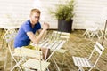 Thoughtful ginger male waiting at a table outdoors