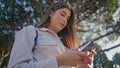 Thoughtful girl browsing smartphone in sunny park. Closeup woman messaging Royalty Free Stock Photo