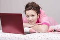 Thoughtful girl in bed works for laptop Royalty Free Stock Photo