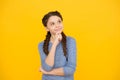 Thoughtful girl with braids. adorable daydreaming kid. think about future. Portrait of pensive teen girl on yellow Royalty Free Stock Photo