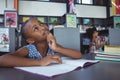 Thoughtful girl looking up at desk in library Royalty Free Stock Photo