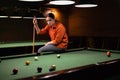 Thoughtful girl plays billiards. Billiard room on the background. Royalty Free Stock Photo