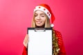 Thoughtful girl in a red sweater and Santa hat, holding a tablet Royalty Free Stock Photo