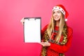 Thoughtful girl in a red sweater and Santa hat, holding a tablet Royalty Free Stock Photo