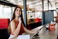 A thoughtful girl is sitting in a cafe using a tablet, making notes in a notebook. Royalty Free Stock Photo