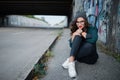 Thoughtful girl sitting on an empty highway under the bridge and thinks Royalty Free Stock Photo