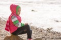 Thoughtful girl sitting on a rock on stony beach of the sea and looks into the distance Royalty Free Stock Photo