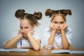 Thoughtful girls sitting at desk on gray background. school concept Royalty Free Stock Photo