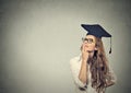 Thoughtful graduate graduated student young woman in cap gown looking up thinking Royalty Free Stock Photo