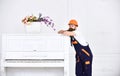 Thoughtful guy leaning on the top of vintage white piano with glass flower vase isolated on white background. Bearded Royalty Free Stock Photo