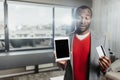 Thoughtful guy standing inside with tablet and credit card