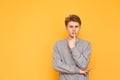 Thoughtful guy stands on a yellow background and looks at the camera. Serious young man is isolated on a yellow background, Royalty Free Stock Photo