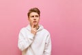 Thoughtful guy in white roe deer stands on a pink background and looks away at copy space with a serious face. Serious young man Royalty Free Stock Photo