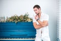 Thoughtful, handsome man with a beard in white clothes against the background of a piano, a rasped shirt with a bare torso