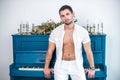 Thoughtful, handsome man with a beard in white clothes against the background of a piano, a rasped shirt with a bare torso