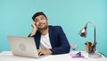 Thoughtful handsome man resting and dreaming sitting in office, making break during work on laptop, fantasizing