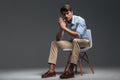 Thoughtful handsome young man sitting on chair and looking camera Royalty Free Stock Photo