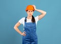Thoughtful handywoman in protective helmet and coveralls touching head in confusion