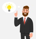 Thoughtful happy businessman pointing up to the bright bulb in the thought bubble. Idea, innovation, invention,problem solving, s.