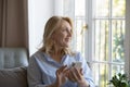 Thoughtful happy senior smartphone user woman sitting on home sofa Royalty Free Stock Photo