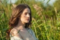 Thoughtful healthy young brunette woman with fresh clear skin and long dark brown hair outdoors on green grass background, air Royalty Free Stock Photo