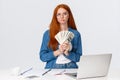Thoughtful and hesitant serious-looking redhead female got payed, won big money prize in online art competition