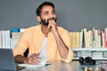 Thoughtful indian businessman working thinking listening podcast at home office. Royalty Free Stock Photo