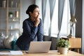 Thoughtful Indian woman standing at desk, pondering task