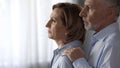 Thoughtful lady standing by window, male taking her by shoulders, hard times