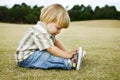 A thoughtful little boy sitting on the grass in a Royalty Free Stock Photo