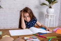 Thoughtful little girl at the table draw with crayons Royalty Free Stock Photo