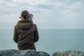 Thoughtful lonely man with dreadlocks sit by sea shore in cloudy day. Depression, loneliness, crisis, mental problems Royalty Free Stock Photo