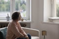 Thoughtful lonely retired woman sitting on couch at home