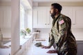 Thoughtful Male American Soldier In Uniform In Kitchen On Home Leave Looking Out Of Window Royalty Free Stock Photo