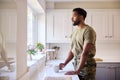 Thoughtful Male American Soldier In Uniform In Kitchen On Home Leave Looking Out Of Window Royalty Free Stock Photo