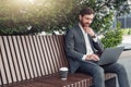 Thoughtful male businessman working on laptop at lunchtime sitting on bench near office Royalty Free Stock Photo