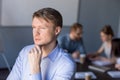 Thoughtful male employee looks in distance thinking about succes