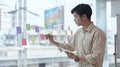 Thoughtful male employee writing information on colorful sticky notes develop business project.