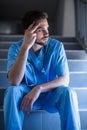 Thoughtful male nurse sitting on staircase