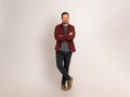 Thoughtful man with arms crossed looking away while standing isolated against background. Handsome young man dressed in maroon