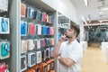 Thoughtful man chooses cases for a smartphone in the accessories department at the modern electronics store