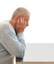 Thoughtful man with a depressed facial expression holds his head with his hands by a table. Close-up image on white