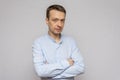 A thoughtful man in a light shirt, looking into the camera, on an isolated gray background. Royalty Free Stock Photo