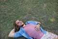 Thoughtful man lying on grass with hand behind head