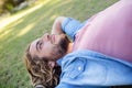 Thoughtful man lying on grass with hand behind head Royalty Free Stock Photo