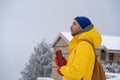 Pensive man walks near home with hot drink in thermal bottle thinking question at winter frosty day.