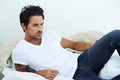 Thoughtful and masculine. handsome man wearing a white t-shirt and lying on a bed. Royalty Free Stock Photo