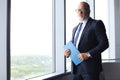 Thoughtful mature business man in full suit looking away while standing near the window. Royalty Free Stock Photo