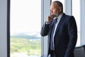 Thoughtful mature business man in full suit looking away while standing near the window Royalty Free Stock Photo