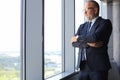 Thoughtful mature business man in full suit looking away while standing near the window Royalty Free Stock Photo